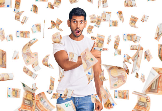 Young latin man wearing casual clothes surprised pointing with finger to the side, open mouth amazed expression.