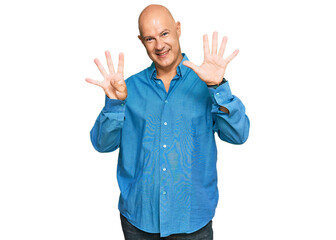 Middle age bald man wearing casual clothes showing and pointing up with fingers number nine while smiling confident and happy.