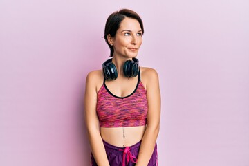 Obraz premium Young brunette woman with short hair wearing sportswear and headphones smiling looking to the side and staring away thinking.