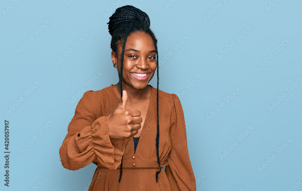 Wall mural young african american woman wearing casual clothes doing happy thumbs up gesture with hand. approvi