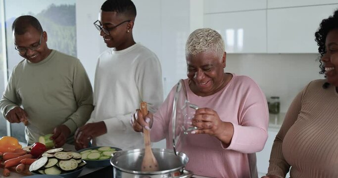 Happy latin family cooking inside kitchen at home - Father, daughter, son and mother having fun preparing lunch