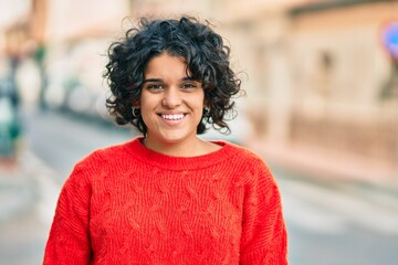 Young hispanic woman smiling happy looking to the camera at the city.