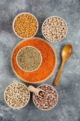 Bowls of various uncooked beans, lentils and corns on marble surface