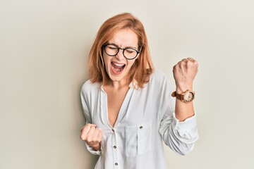 Young caucasian woman wearing casual clothes and glasses celebrating surprised and amazed for success with arms raised and eyes closed