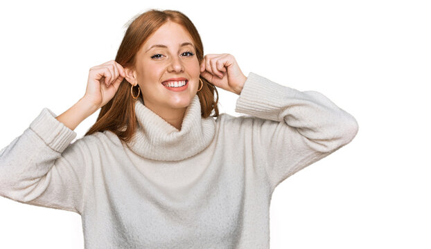 Young irish woman wearing casual winter sweater smiling pulling ears with fingers, funny gesture. audition problem