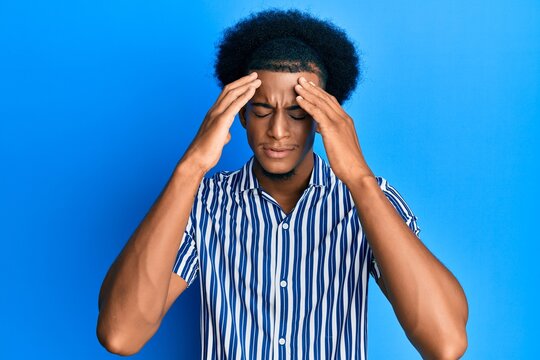 African american man with afro hair wearing casual clothes with hand on head, headache because stress. suffering migraine.