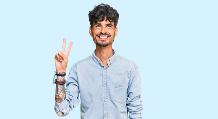 Young hispanic man wearing casual clothes showing and pointing up with fingers number two while smiling confident and happy.