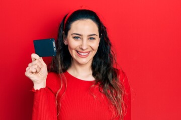 Naklejka premium Young hispanic woman holding ssd memory looking positive and happy standing and smiling with a confident smile showing teeth