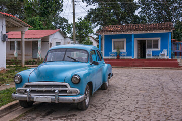 Viejo coche americano junto a unas casas en el pueblo de Viñales, Cuba