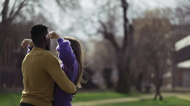 Black man kissing white girlfriend standing outside at park