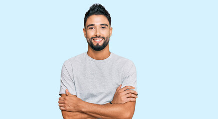 Young man with beard wearing casual grey tshirt happy face smiling with crossed arms looking at the...
