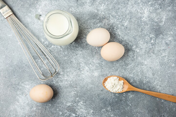 Bowl of flour, eggs and whisker on marble background