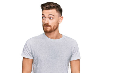 Fototapeta premium Young redhead man wearing casual grey t shirt smiling looking to the side and staring away thinking.