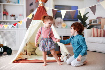 cute happy siblings playing together in nursery room at home