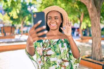 Fototapeta premium Young african american tourist woman on vacation smiling happy doing video call using smartphone at the city.