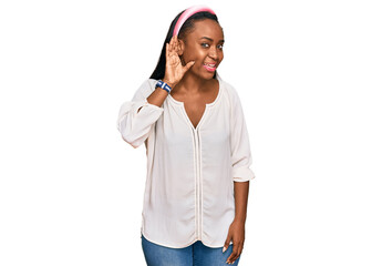 Young black woman wearing casual clothes smiling with hand over ear listening an hearing to rumor or gossip. deafness concept.