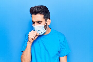 Young handsome man with beard wearing medical mask feeling unwell and coughing as symptom for cold or bronchitis. health care concept.
