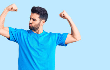 Fototapeta premium Young handsome man with beard wearing casual t-shirt showing arms muscles smiling proud. fitness concept.