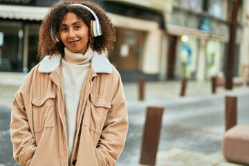 Young african american woman listening to music at the city.