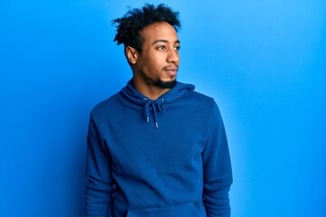 Young african american man with beard wearing casual sweatshirt looking to side, relax profile pose with natural face and confident smile.
