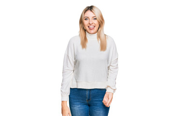 Young caucasian woman wearing casual winter sweater sticking tongue out happy with funny expression. emotion concept.