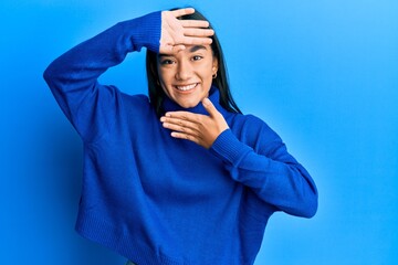 Young asian woman wearing casual winter sweater smiling cheerful playing peek a boo with hands showing face. surprised and exited