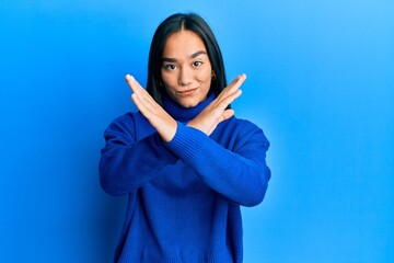 Young asian woman wearing casual winter sweater rejection expression crossing arms doing negative sign, angry face