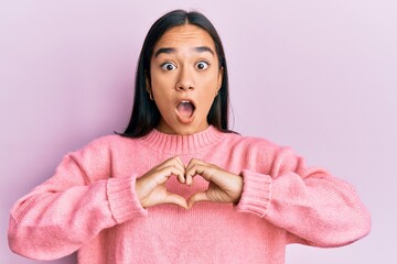 Young asian woman doing heart symbol with hands afraid and shocked with surprise and amazed expression, fear and excited face.