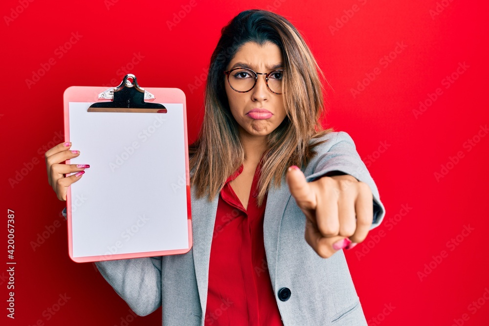 Canvas Prints Beautiful brunette woman holding clipboard with blank space depressed and worry for distress, crying angry and afraid. sad expression.