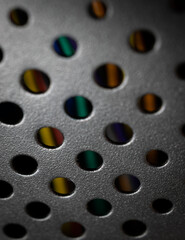 Black metal surface with round holes in it