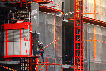 Elevator used for worker and moving materials, Construction site and workplace, Engineer working inspecting outdoor passenger lift system, Development land and residential building structure in city.
