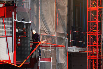 Engineer working cutting or welding steel and inspecting outdoor passenger lift system, Elevator...