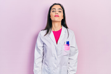 Young hispanic girl wearing scientist uniform with serious expression on face. simple and natural looking at the camera.