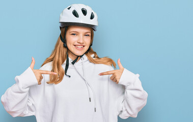 Beautiful young caucasian girl wearing bike helmet looking confident with smile on face, pointing oneself with fingers proud and happy.