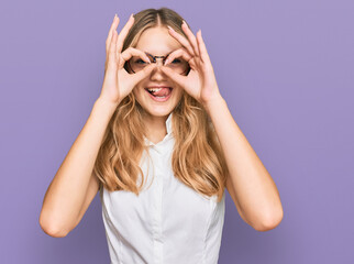 Beautiful young caucasian girl wearing casual clothes and glasses doing ok gesture like binoculars sticking tongue out, eyes looking through fingers. crazy expression.