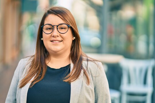Young hispanic plus size businesswoman smiling happy standing at the city.