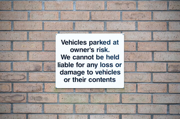 Fototapeta na wymiar Car park users do so at own risk sign