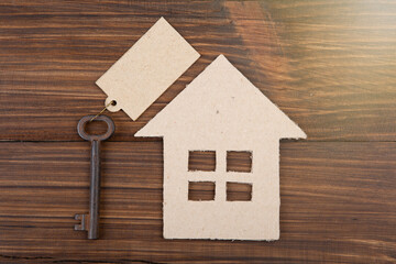 Obraz na płótnie Canvas Real estate concept -Buying,selling or rent a house. Old key with tag and cardboard house on wooden background
