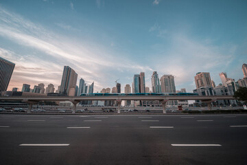 Obraz premium Moving Dubai metro train on the bridge against upscale community skyline. Panoramic view for a modern city and infrastructure. Dubai Metro against skyline at Sheikh Zayed road.
