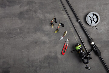 Fishing tackle - fishing spinning rod, hooks and lures on gray background. Active hobby recreation...