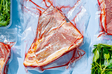 vacuum packed raw beef steaks ready to fry. t-bone steak from marbled beef. meat and vegetables