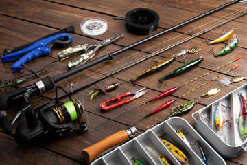 Fishing tackle - fishing spinning rod, hooks and lures on wooden background. Active hobby...