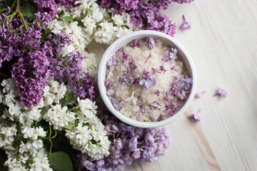 Obraz na płótnie Canvas Homemade bath salt with fresh spring lilac flowers, home healthy spa, relaxation, light wooden background, top view from above