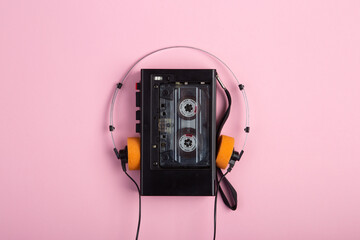 Music listening concept. Vintage cassette tape, audio player and headphones close-up on pink background, top view.