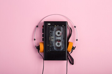 Music listening concept. Vintage cassette tape, audio player and headphones close-up on pink...
