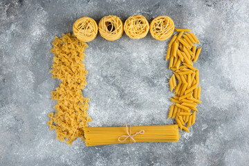 Various uncooked pasta on stone background