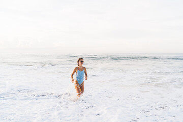 Fototapeta na wymiar Young woman standing in foamy seawater