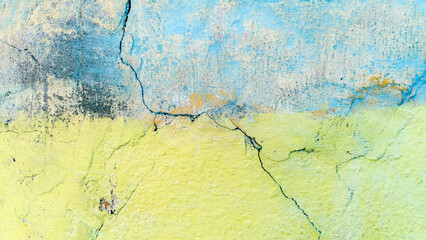 A weathered old wall painted in pastel shades of yellow and blue.