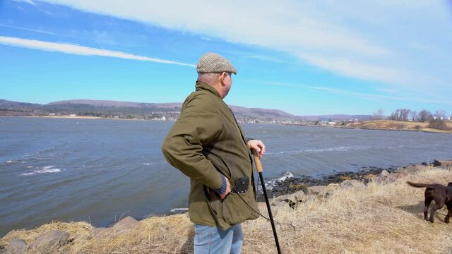 A mature man walking in pain.  A man in his late fifties walking his dog.  