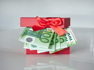 A red gift box filled with Euro currency money. Banknotes with a nominal value of 100 euros.